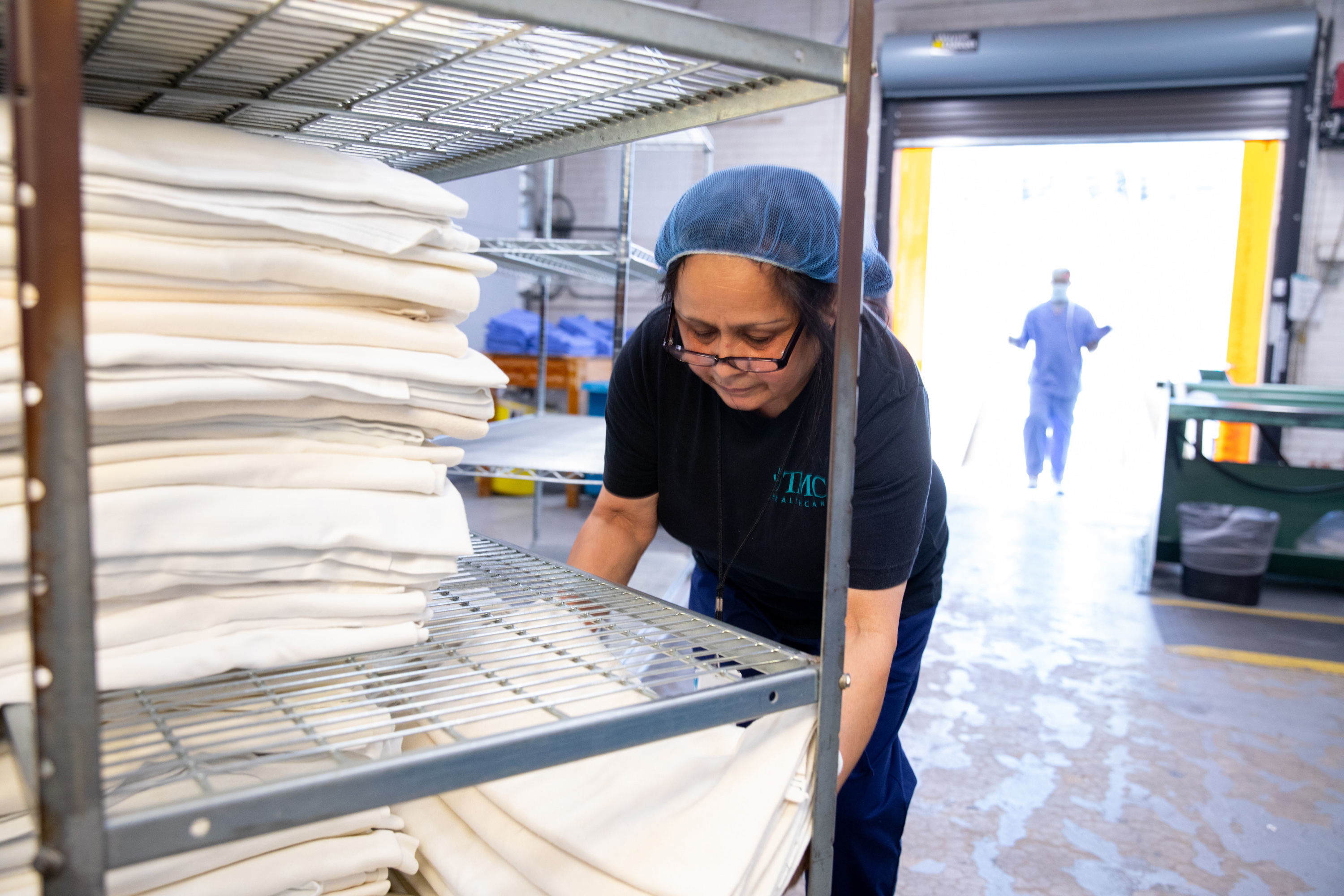 Laundry staff placing clean linens on a wire rack
