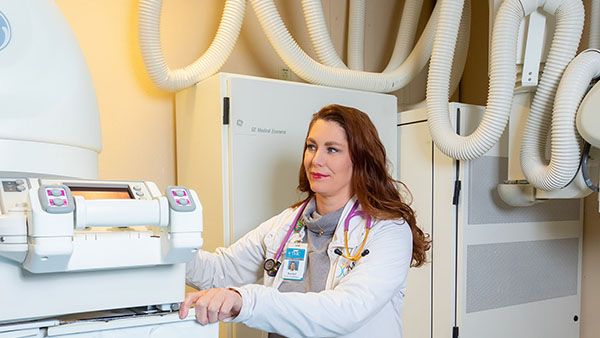  Medical professional operates an imaging machine surrounded by flexible tubing in a clinical setting.