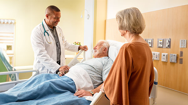 Patient in bed with visitor and doctor standing beside them