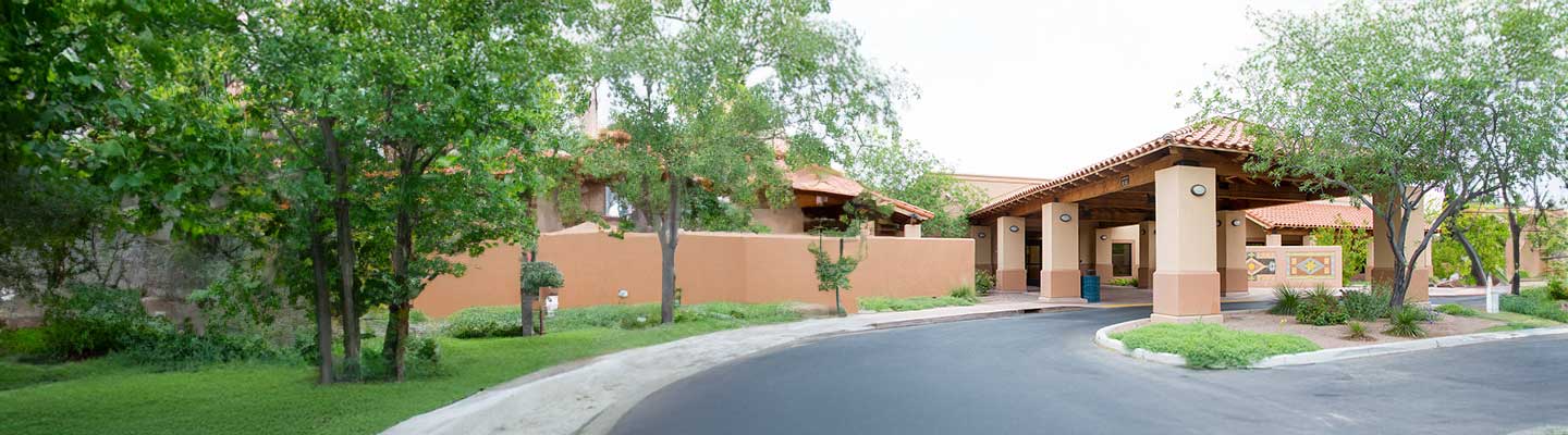 Exterior view of Peppi's House inpatient hospice, a teracotta building with green trees around it.