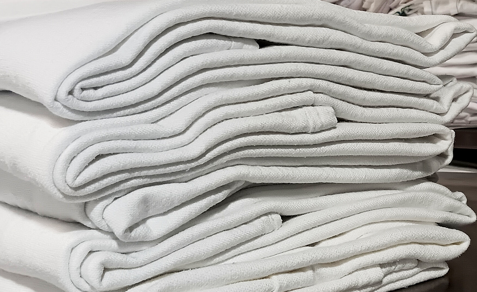 A stack of freshly washed and folded hospital blankets.