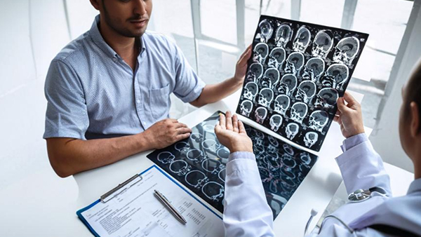 A doctor shows a patient brain MRI scans during a consultation.