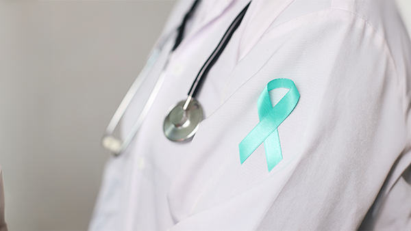 Person wearing a lab coat with a stethoscope and an teal awareness ribbon.