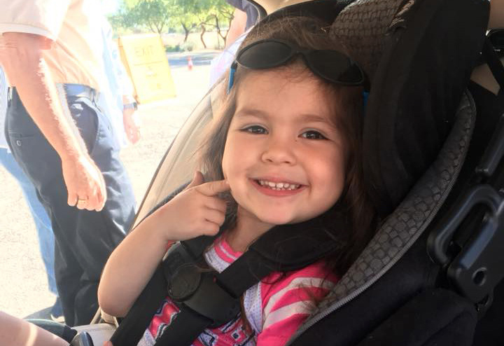 A little girl smiling while sitting in her car seat