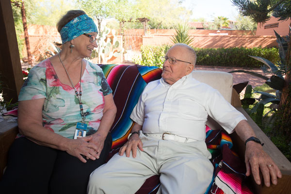 An older man and a hospice volunteer sit together in the Peppi's House garden.