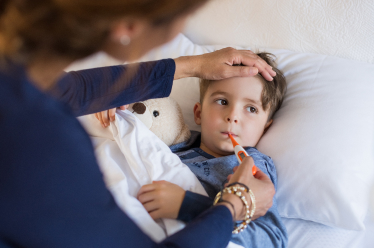 A sick child having their temperature checked with a thermometer